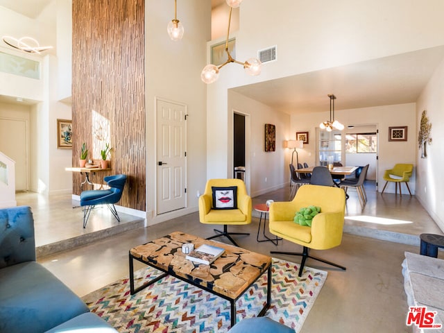 living room with a towering ceiling, concrete floors, and an inviting chandelier