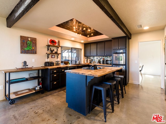 kitchen featuring a center island, beamed ceiling, wooden counters, a kitchen bar, and black stovetop