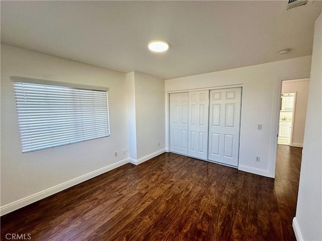 unfurnished bedroom with a closet and dark hardwood / wood-style floors