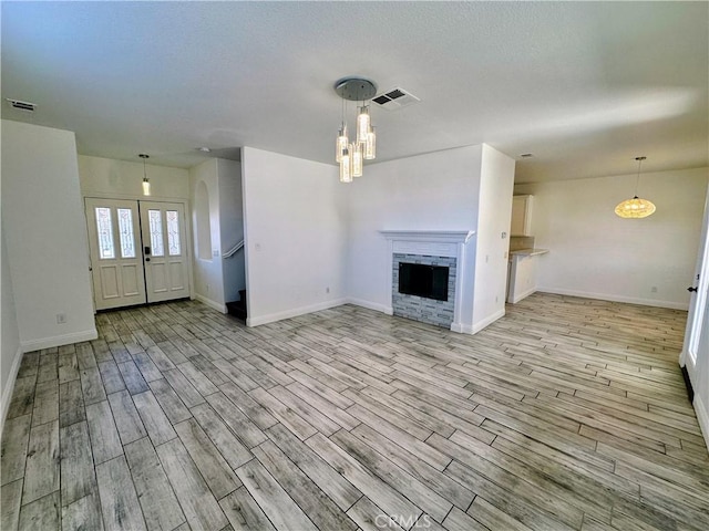 unfurnished living room with a stone fireplace and light hardwood / wood-style flooring