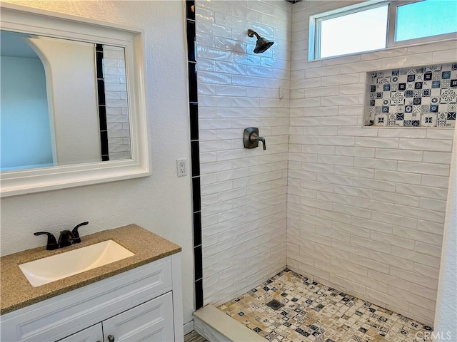 bathroom featuring tiled shower and vanity