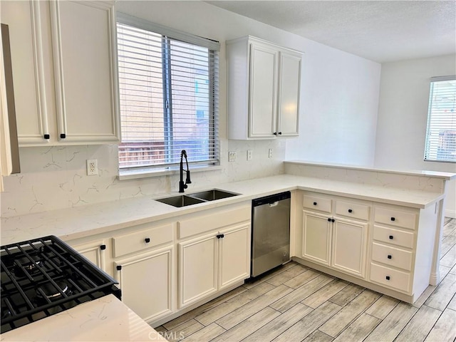 kitchen with light stone counters, sink, dishwasher, and a healthy amount of sunlight