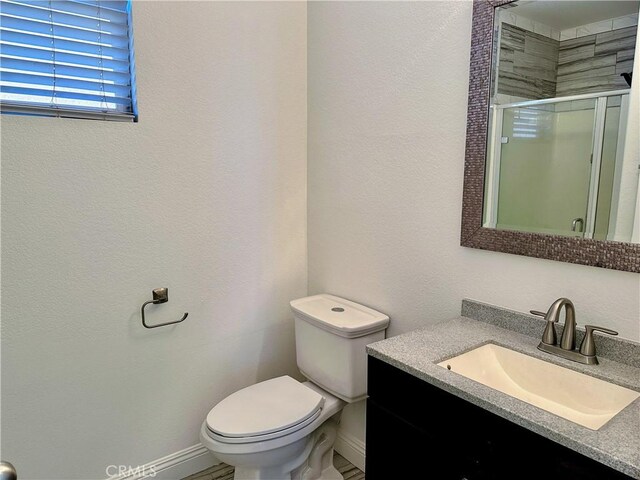 bathroom with toilet, an enclosed shower, and vanity