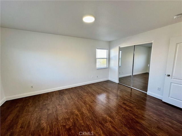 unfurnished bedroom featuring a closet and dark hardwood / wood-style flooring