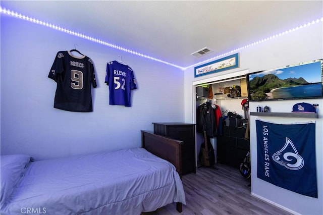 bedroom with hardwood / wood-style floors, ornamental molding, and a closet