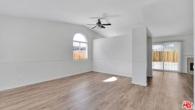 unfurnished room with a fireplace, light wood-type flooring, ceiling fan, and lofted ceiling