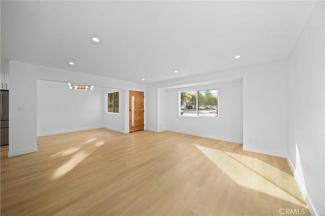 unfurnished living room with light hardwood / wood-style floors and a chandelier