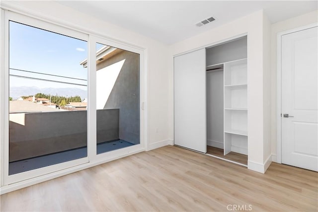 unfurnished bedroom featuring a mountain view, a closet, and light hardwood / wood-style flooring