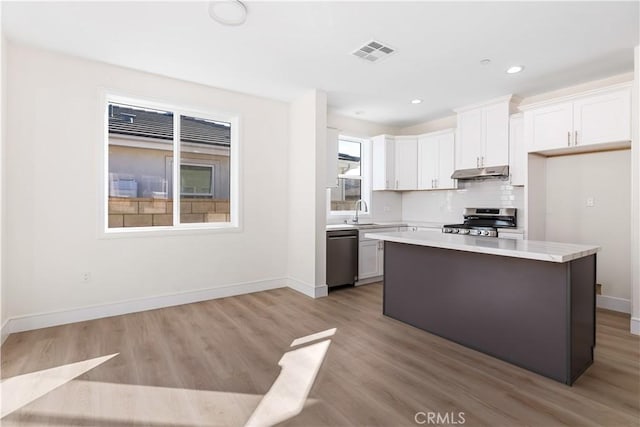 kitchen with white cabinetry, sink, light hardwood / wood-style floors, a kitchen island, and appliances with stainless steel finishes