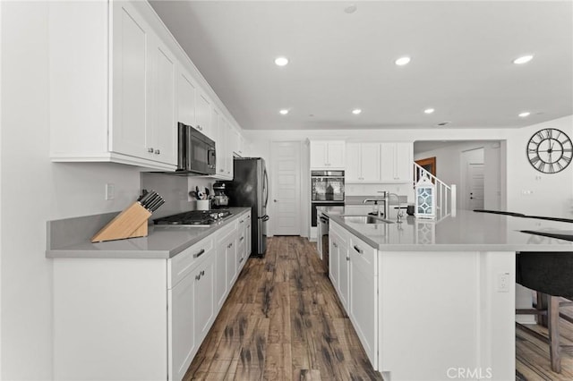 kitchen with stainless steel appliances, an island with sink, dark hardwood / wood-style floors, sink, and white cabinetry