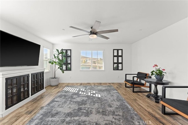 living area with ceiling fan, hardwood / wood-style floors, and a wealth of natural light