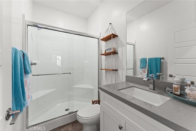 bathroom featuring a shower with door, vanity, and toilet