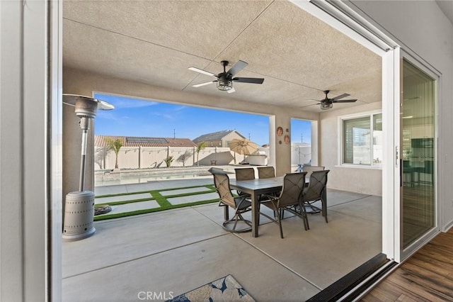 view of patio with ceiling fan and a pool