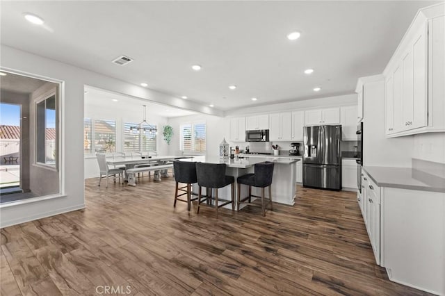 kitchen featuring an island with sink, appliances with stainless steel finishes, a breakfast bar, and white cabinetry