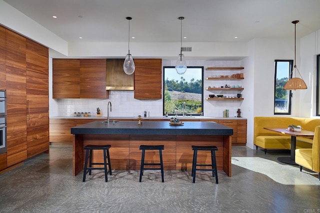 kitchen featuring a breakfast bar, hanging light fixtures, and a center island with sink