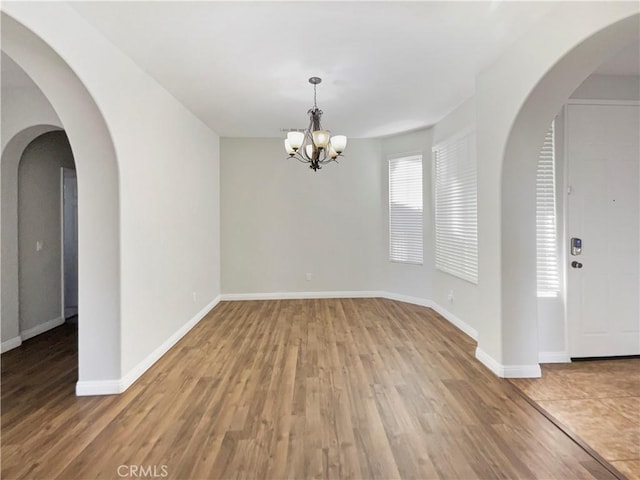 unfurnished room featuring wood-type flooring and a chandelier