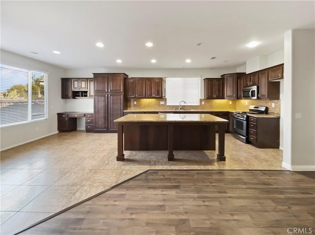 kitchen with appliances with stainless steel finishes, a center island, backsplash, and dark brown cabinetry