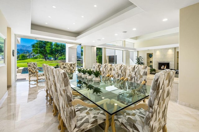 dining area featuring a tray ceiling and a tiled fireplace