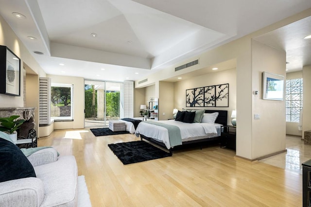 bedroom featuring a tray ceiling and light hardwood / wood-style flooring