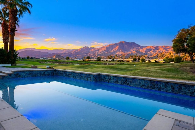 pool at dusk with a mountain view and a lawn