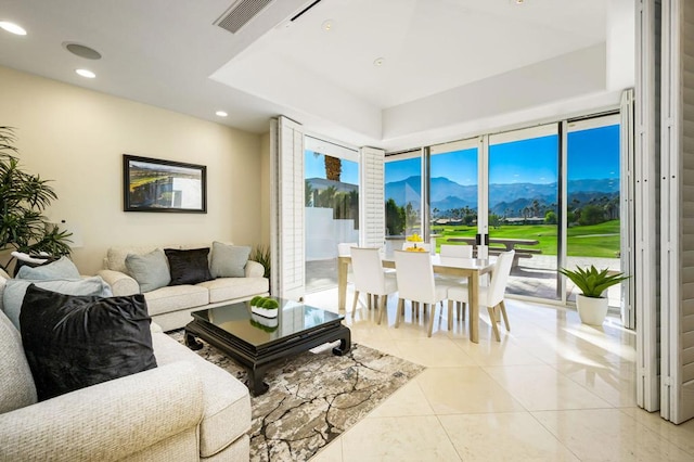 living room with a mountain view, light tile patterned floors, a healthy amount of sunlight, and a wall of windows