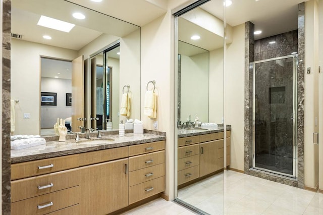 bathroom with a skylight, tile patterned flooring, vanity, and a shower with shower door