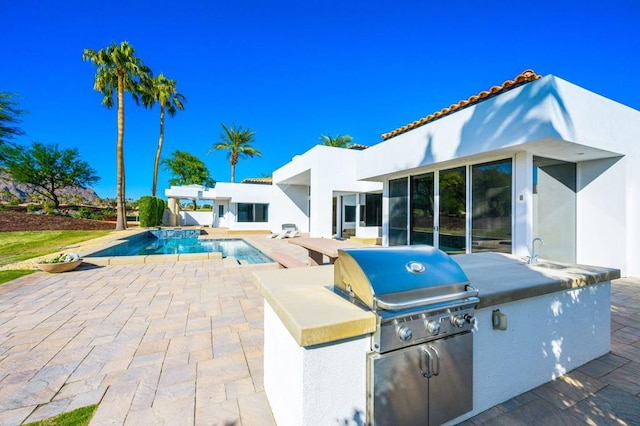 view of swimming pool with area for grilling, a patio area, sink, and grilling area