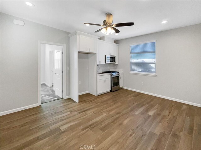 kitchen featuring sink, ceiling fan, appliances with stainless steel finishes, white cabinets, and light wood-type flooring