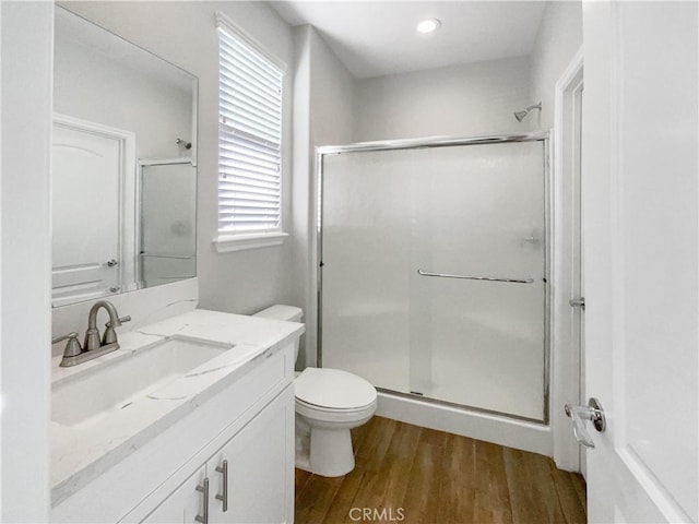 bathroom with hardwood / wood-style flooring, vanity, toilet, and a shower with shower door