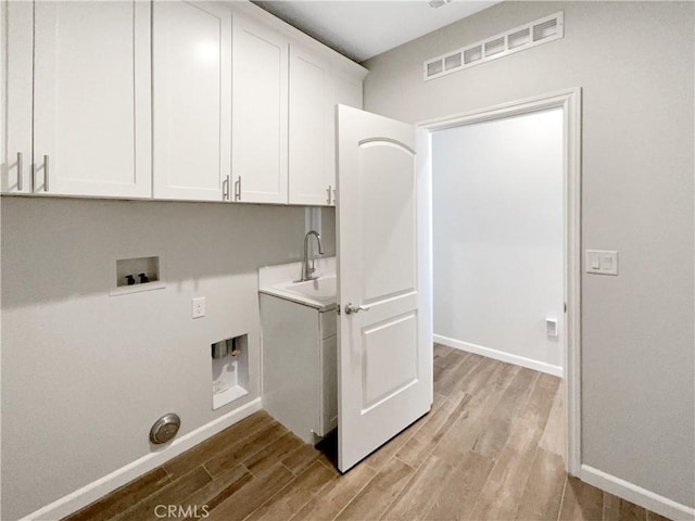 laundry area with cabinets, hookup for a washing machine, sink, and light hardwood / wood-style flooring