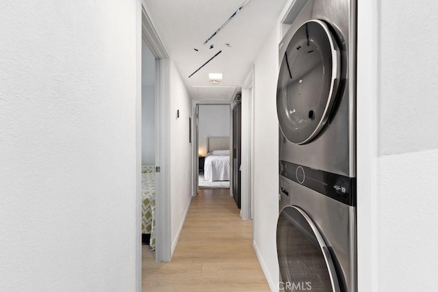 clothes washing area with stacked washing maching and dryer and light wood-type flooring