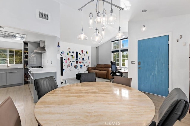 dining room with lofted ceiling, light wood-type flooring, and sink