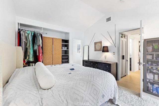 bedroom featuring vaulted ceiling, a closet, and light hardwood / wood-style flooring