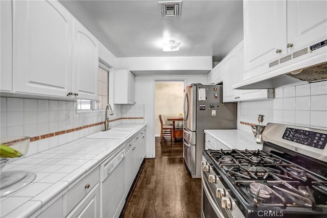 kitchen featuring appliances with stainless steel finishes, backsplash, sink, white cabinets, and dark hardwood / wood-style floors