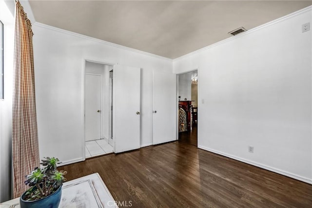 unfurnished bedroom with crown molding and dark wood-type flooring