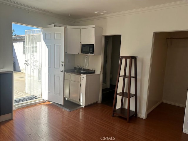 kitchen with sink, crown molding, dark hardwood / wood-style flooring, white cabinetry, and black microwave