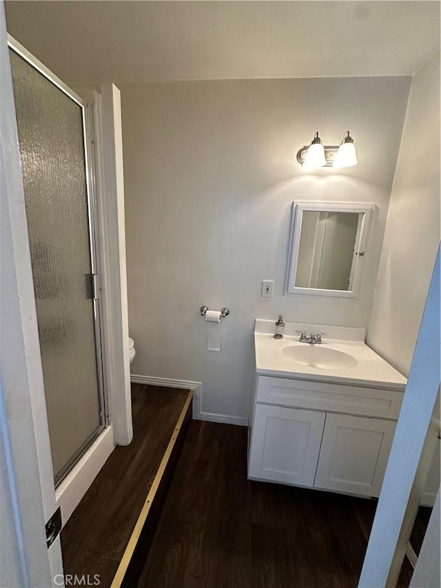 bathroom featuring hardwood / wood-style floors, vanity, toilet, and walk in shower