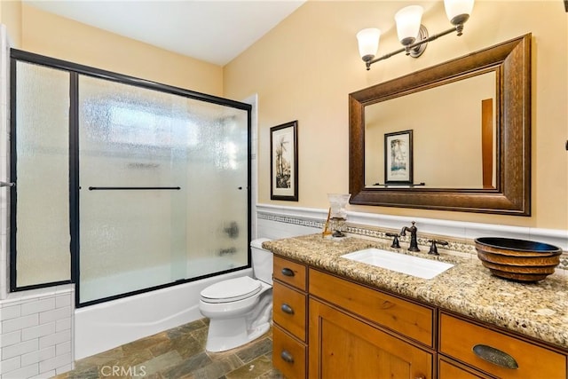 full bathroom with toilet, vanity, bath / shower combo with glass door, and tile walls