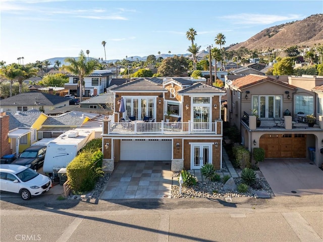 view of front facade with a balcony, french doors, a mountain view, and a garage