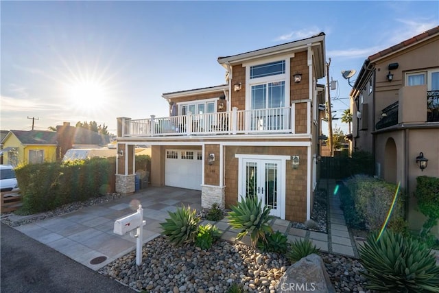 view of front of home featuring french doors, a balcony, and a garage