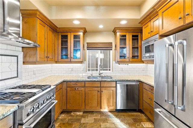 kitchen with sink, high end appliances, decorative backsplash, and wall chimney range hood