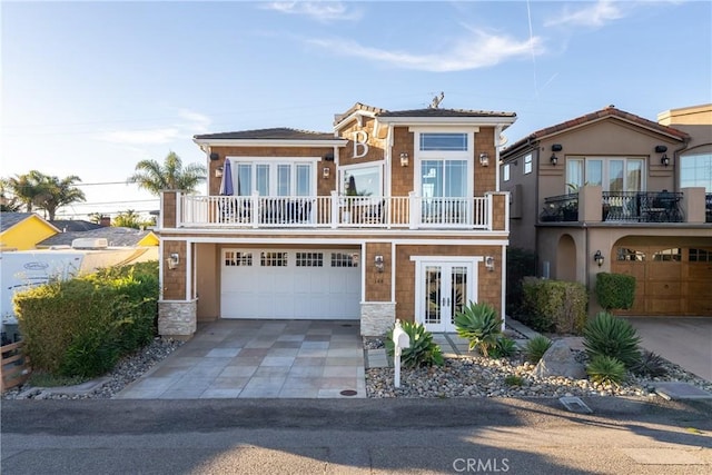 view of front facade featuring french doors, a balcony, and a garage