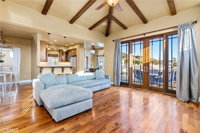 living room featuring ceiling fan with notable chandelier, hardwood / wood-style flooring, and beamed ceiling