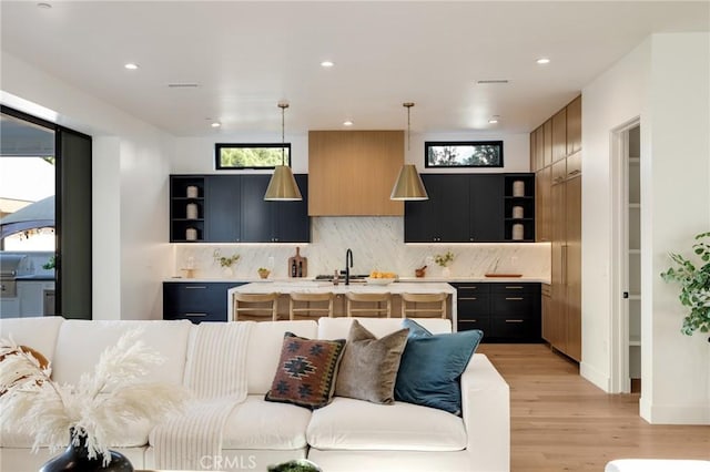 kitchen with plenty of natural light, hanging light fixtures, a center island with sink, and light hardwood / wood-style flooring