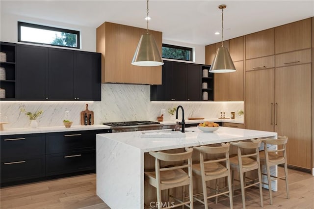 kitchen featuring pendant lighting, a kitchen breakfast bar, light wood-type flooring, and a kitchen island with sink