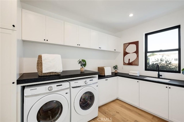 laundry room with cabinets, sink, light hardwood / wood-style floors, and independent washer and dryer