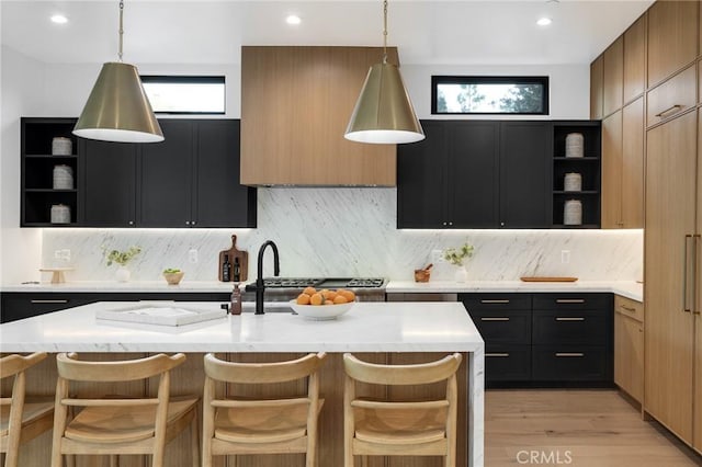 kitchen featuring a kitchen breakfast bar, a kitchen island with sink, and a healthy amount of sunlight