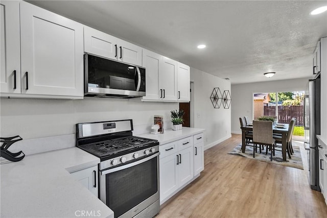 kitchen with stainless steel appliances, white cabinetry, and light wood-type flooring