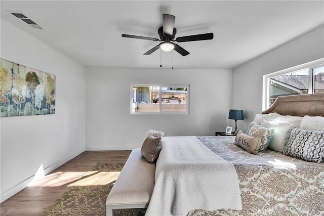 bedroom with ceiling fan, wood-type flooring, and multiple windows