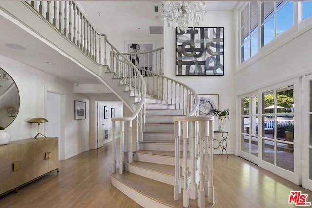 stairway featuring a chandelier, hardwood / wood-style floors, and a towering ceiling